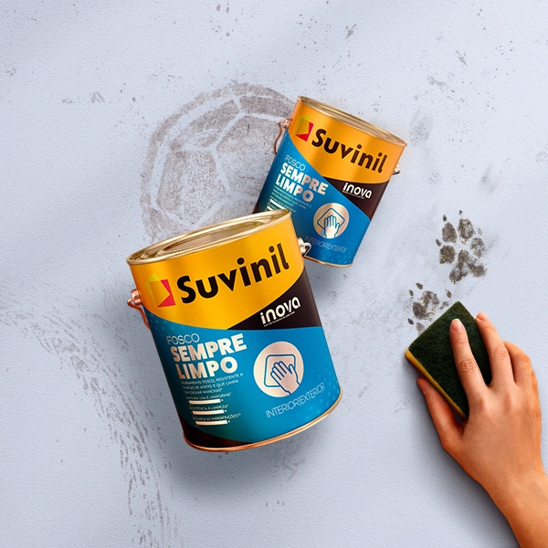 Pessoa utilizando uma esponja para limpar uma parede  com manchas/sujeiras de bola e de patinha de pet.